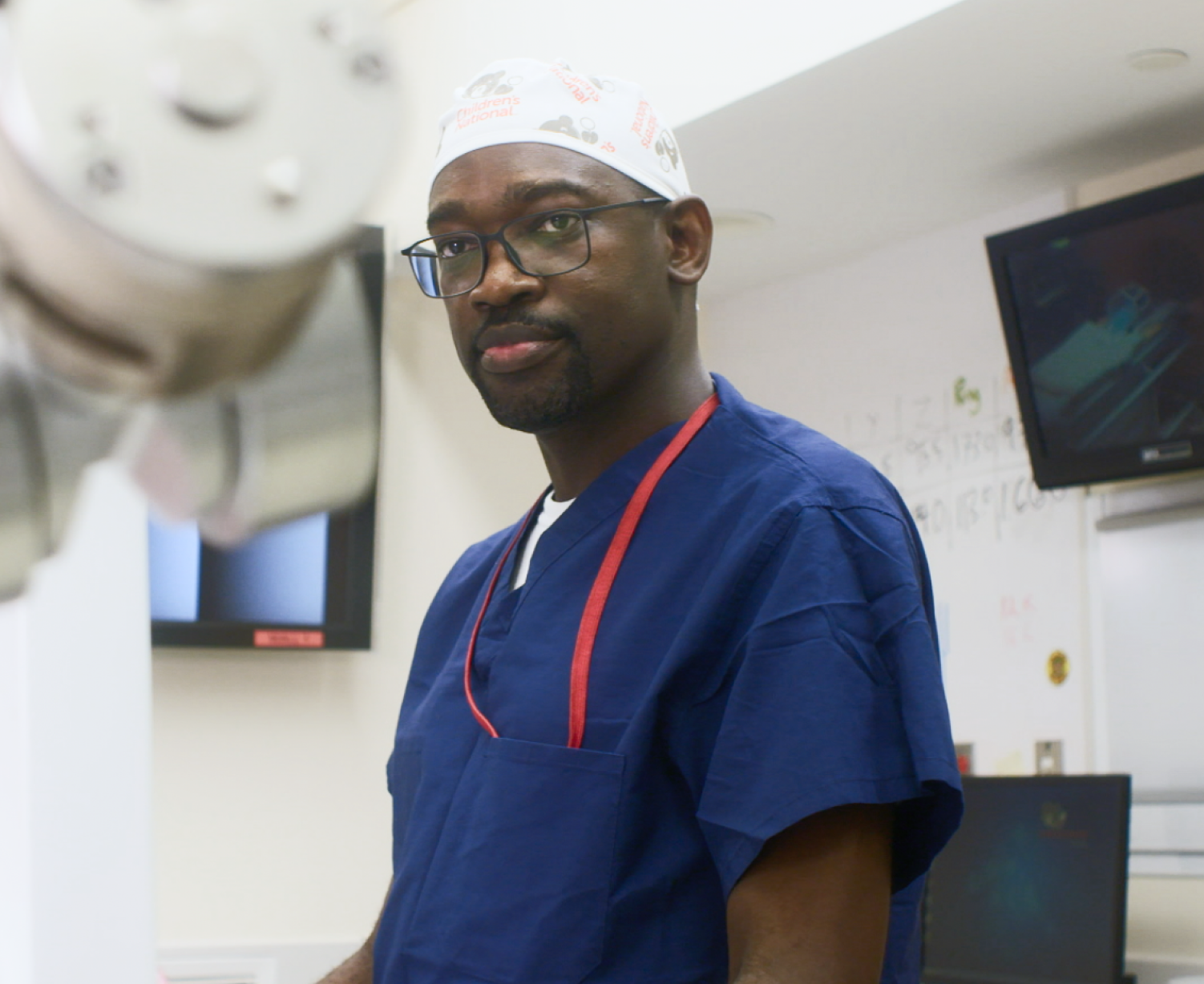 A doctor in blue scrubs, surrounded by medical equipment.