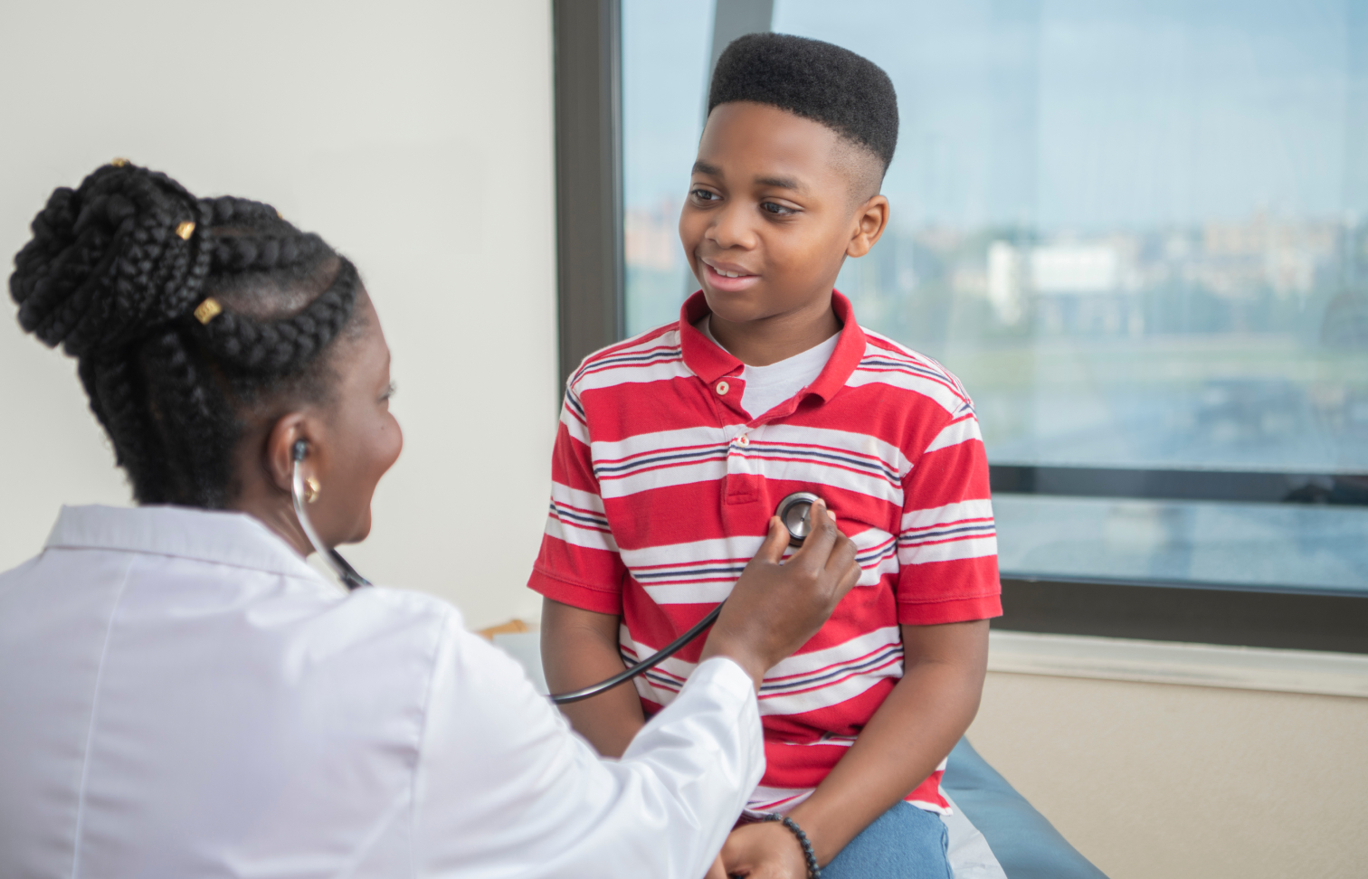 Doctor holding stethoscope to child.