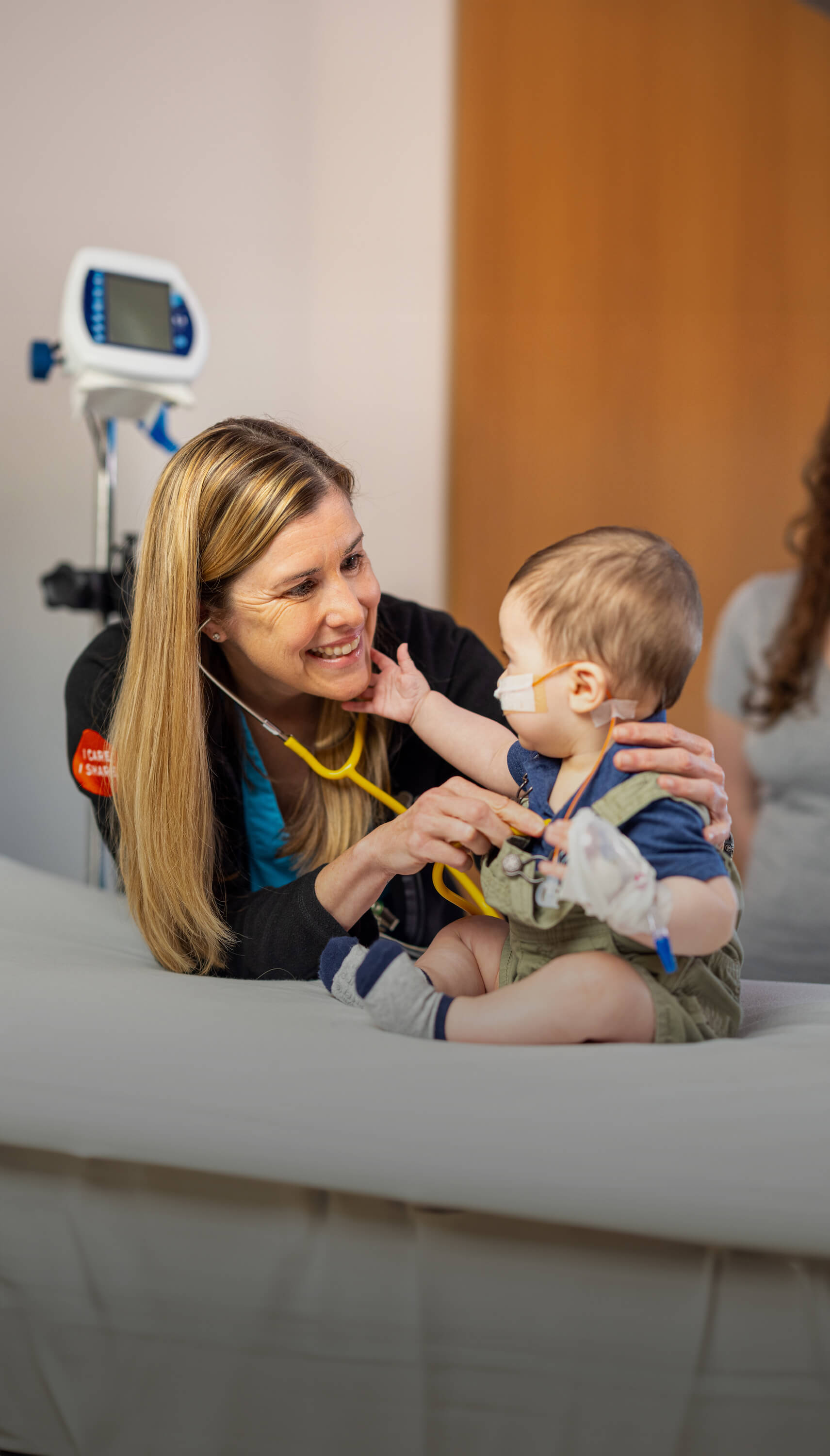 Nurse smiling and listening to a childs heart beating
