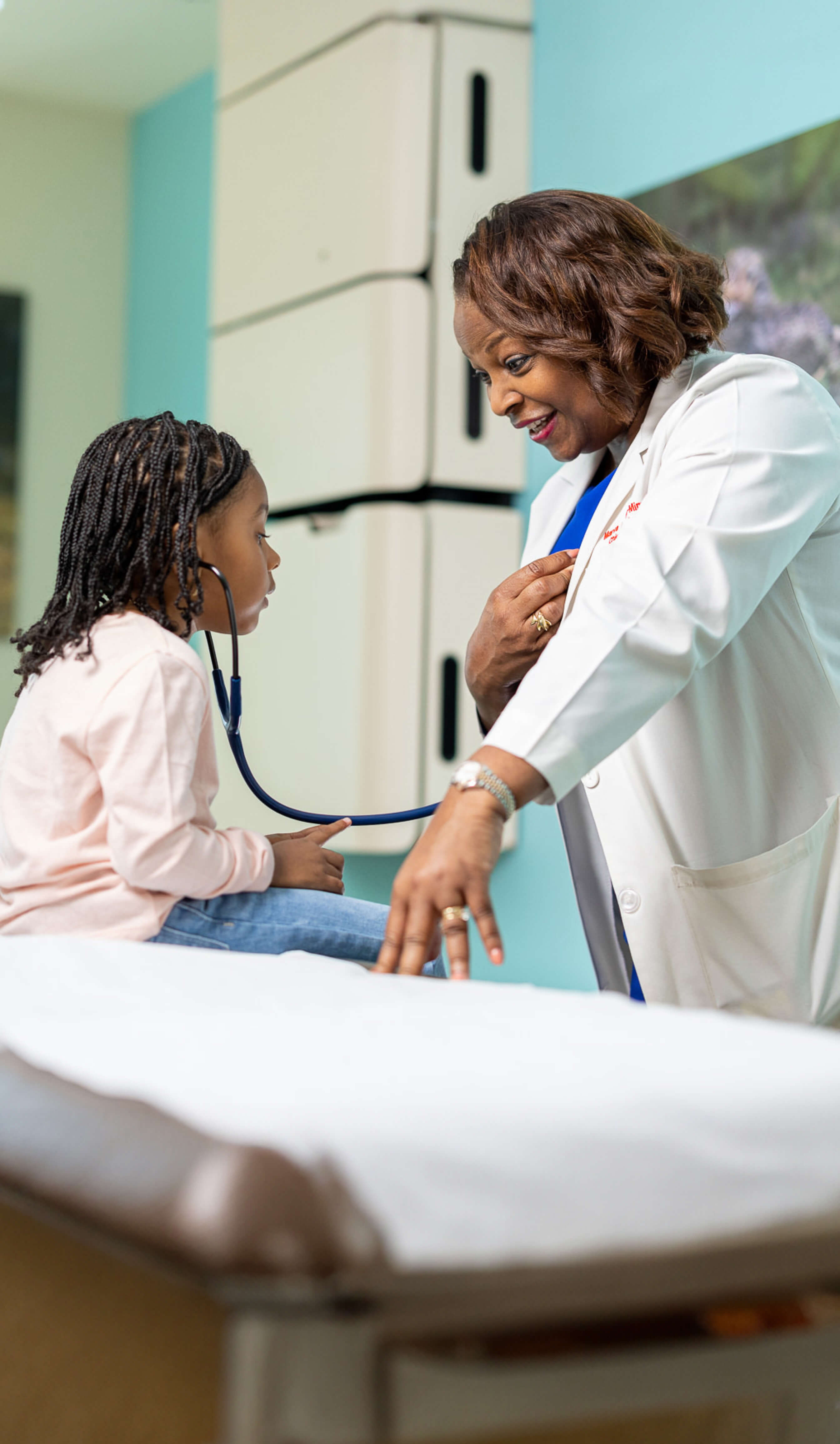 Child listening to a doctors heartbeat through a stethoscope.